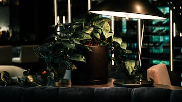 A modern lamp with a black shade, a potted plant, and a bar area in the background.