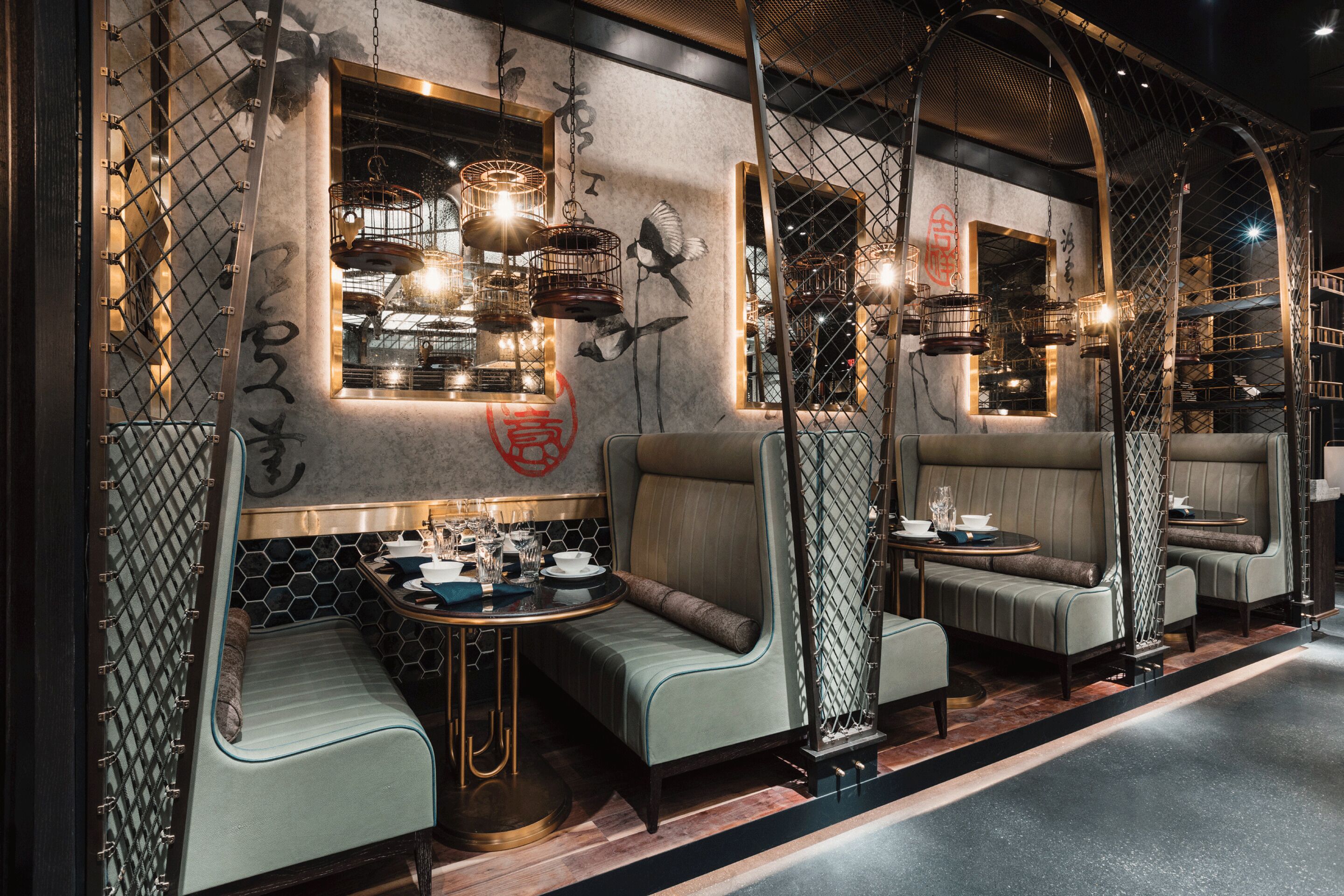 A modern interior with seating areas, a dining table, and decorative birdcages.