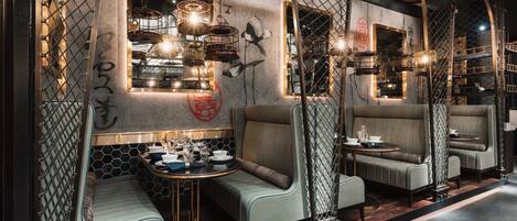 A modern interior with seating areas, a dining table, and decorative birdcages.