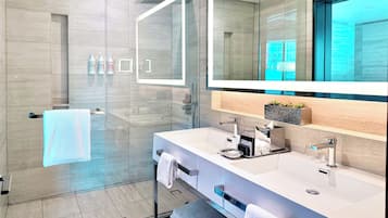 Un baño moderno con cabina de ducha de vidrio, un espejo grande y un mueble de tocador con lavamanos dobles y un perchero.