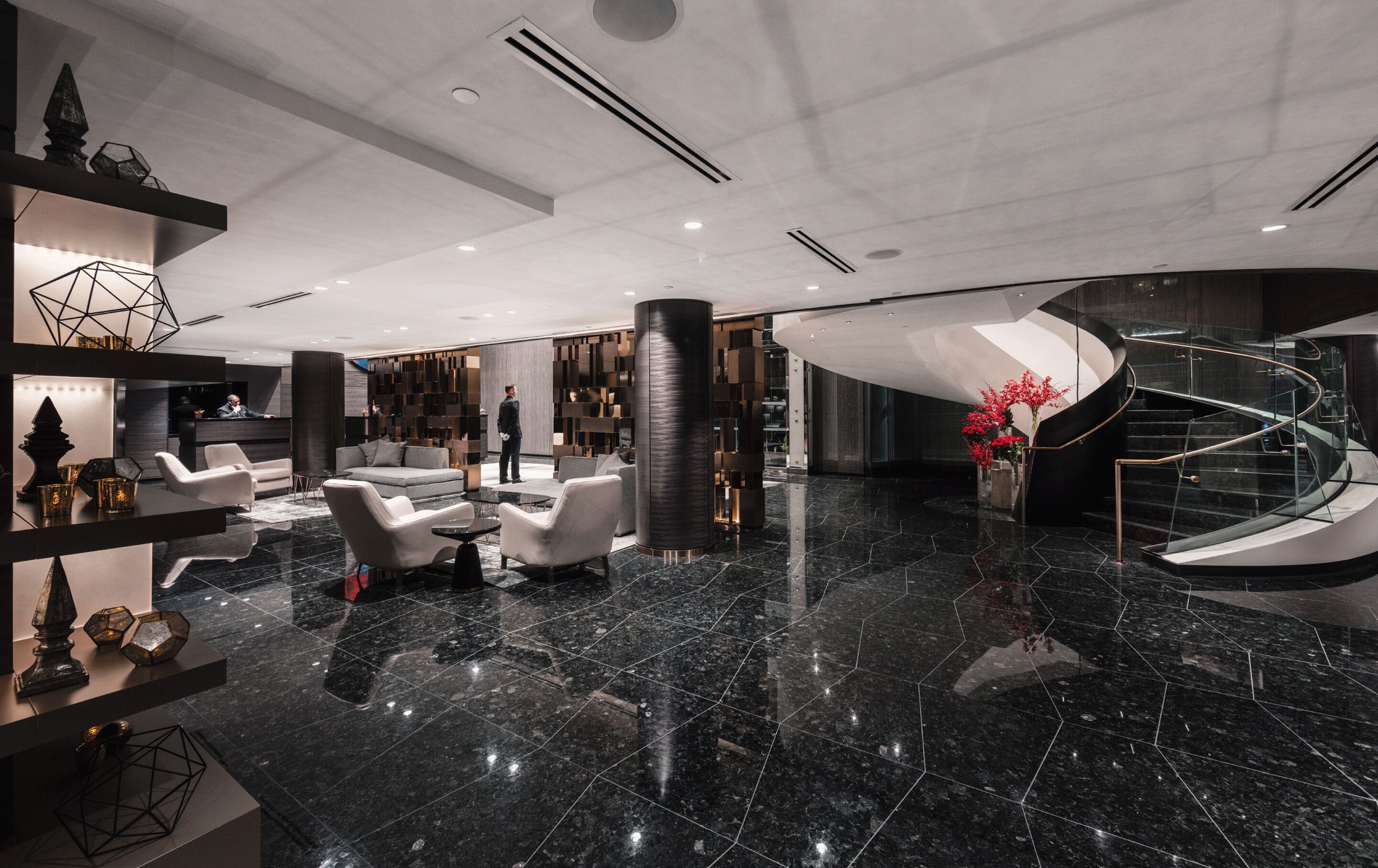 A modern lobby with a marble floor, seating area, and a spiral staircase.
