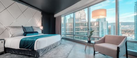 Une chambre d’hôtel moderne dotée d’un grand lit, d’un canapé, d’une petite table avec une lampe et d’une grande fenêtre donnant sur la ville.