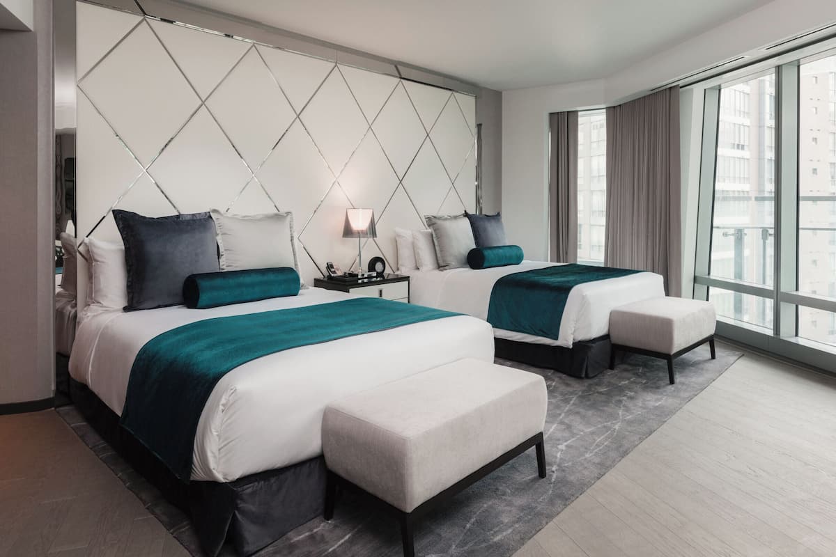 Una habitación de hotel moderna con dos camas, un ventanal grande y vistas a la ciudad.
