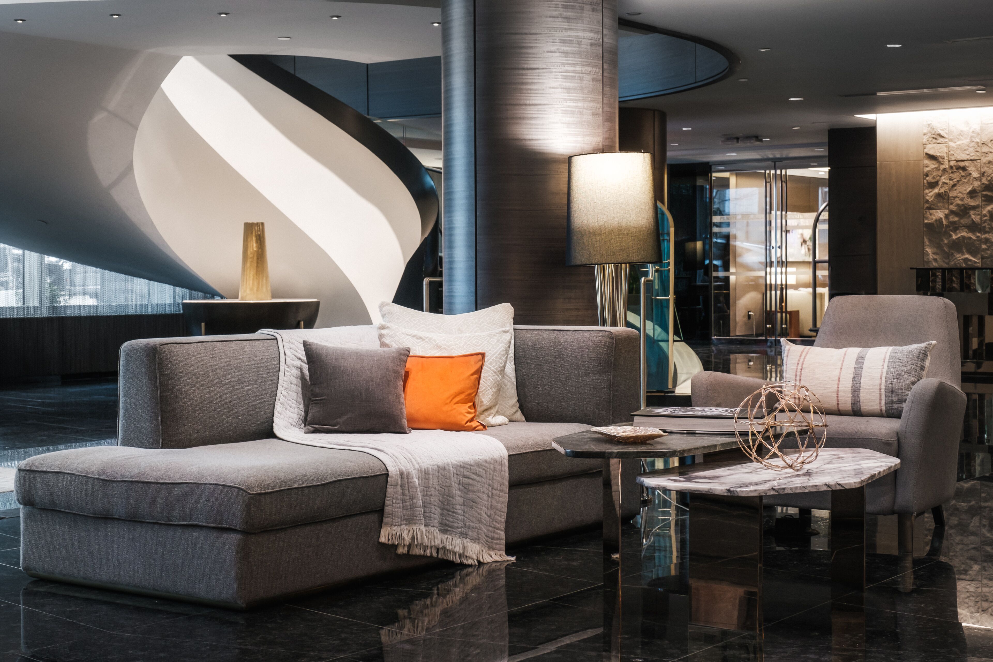 Eine moderne Lobby mit einer gewölbten Wand, einer Sofagarnitur, einem Couchtisch und einer Lampe.