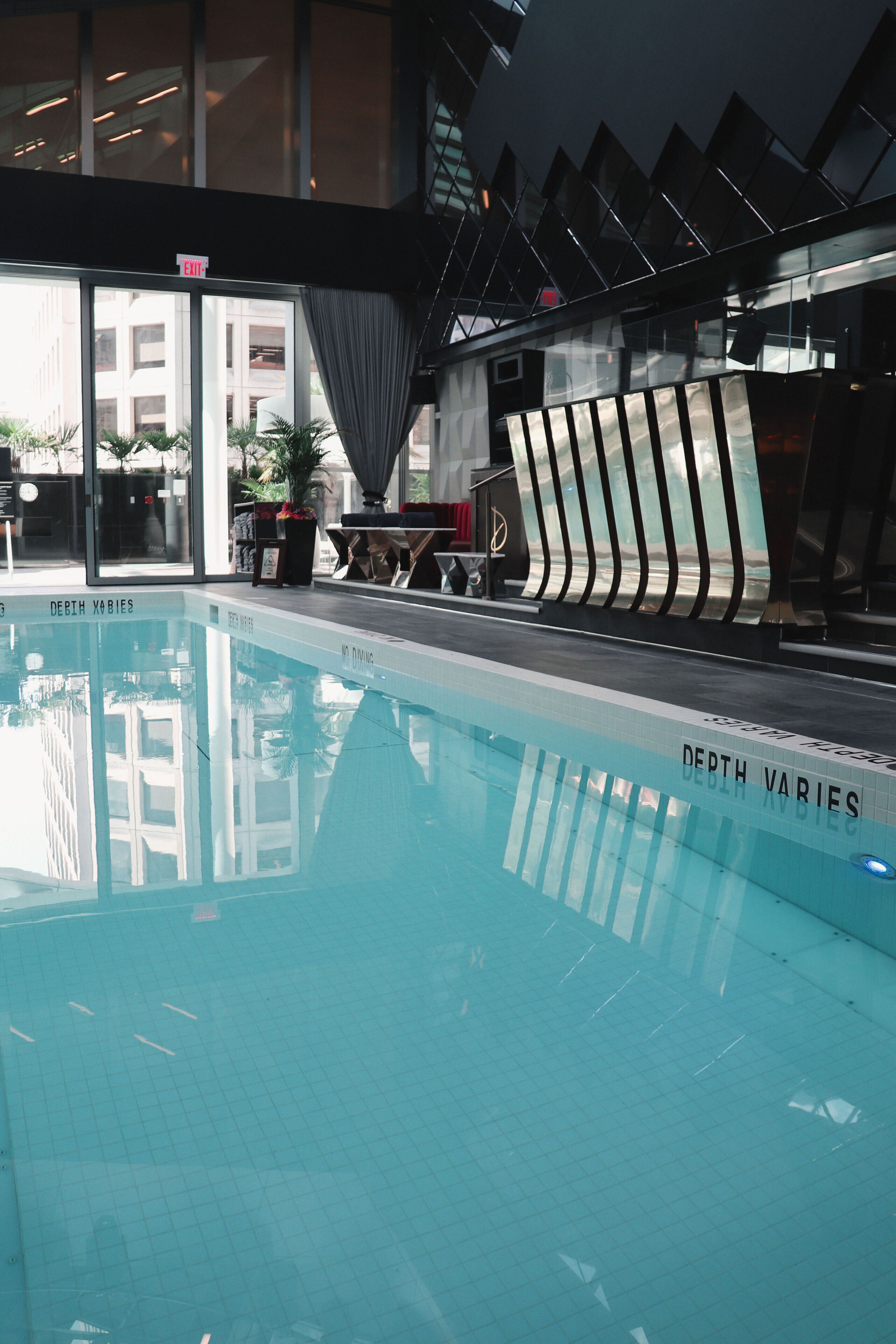 An indoor swimming pool with a clear view of the surrounding area, including a potted plant and a sign indicating 'EXIT'.