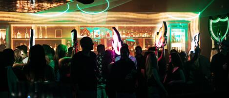 Un bar concurrido con luces de neón y una barra.