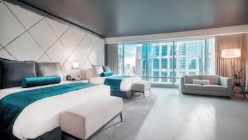 A modern hotel room with two beds, a sofa, and a large window offering a city view.