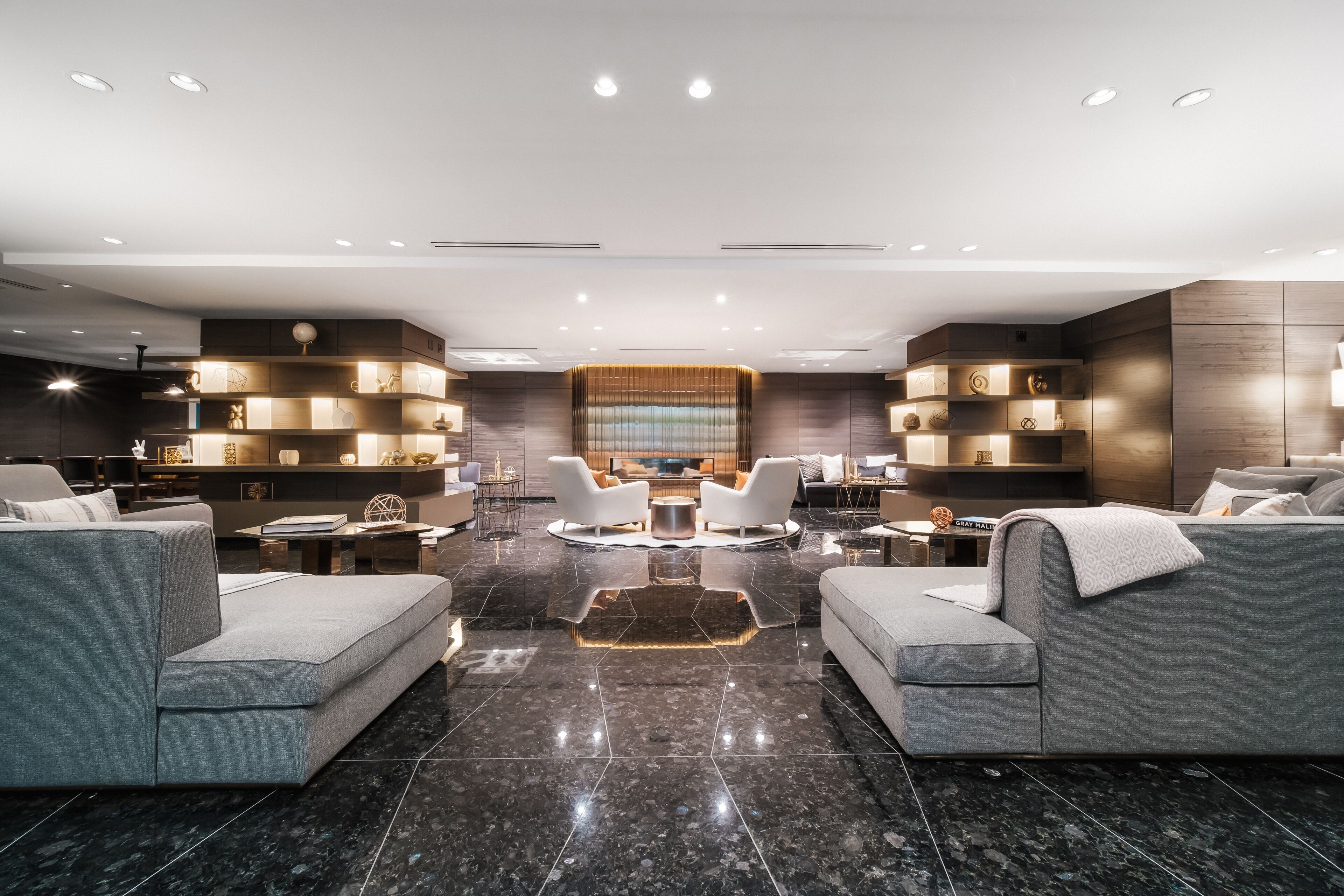 A modern living room with a central seating area, a fireplace, and built-in shelving with decorative items.
