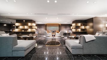 Una sala de estar moderna con una zona de estar central, una chimenea y estanterías empotradas con objetos decorativos.