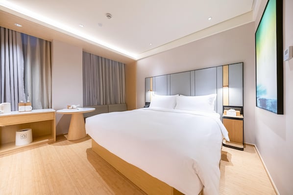 A modern hotel room with a large bed, bedside tables, a round table, and a large mirror. - Ji Hotel (Shanghai)