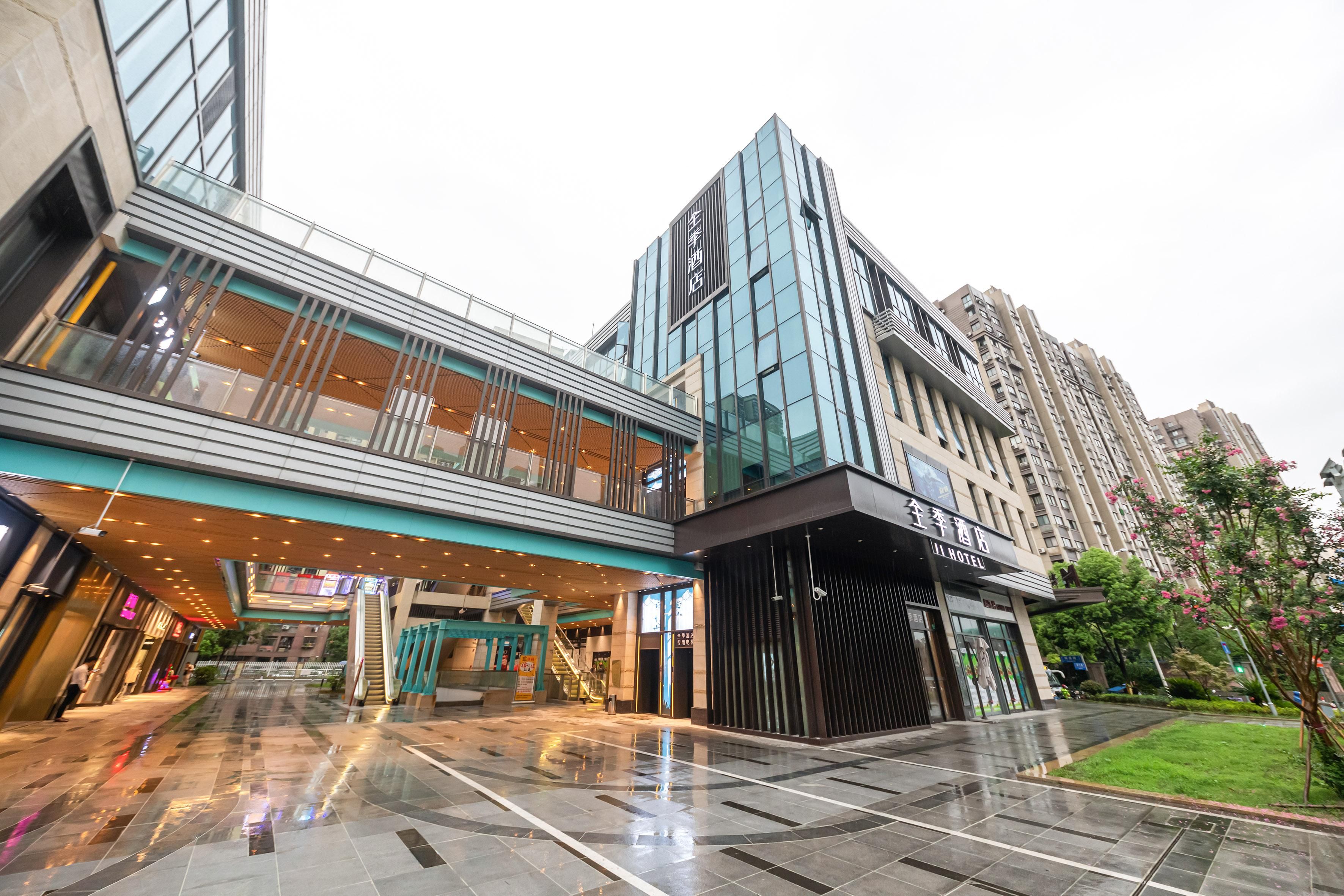 A modern hotel with a glass facade, a covered walkway, and a well-maintained courtyard.