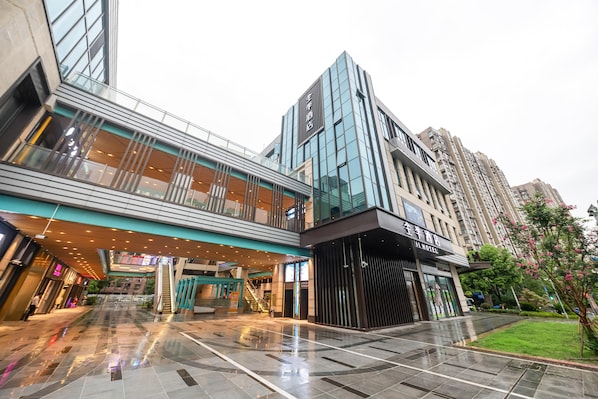 A modern hotel with a glass facade, a covered walkway, and a well-maintained courtyard. - Ji Hotel (Shanghai)