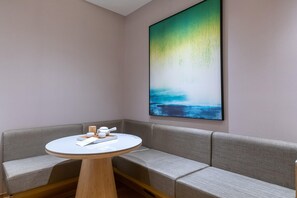 A corner room with a grey sofa, a round table with a white top, and a large abstract painting on the wall. - Ji Hotel (Shanghai)