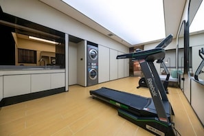 A gym with a treadmill, a washing machine, and a kitchen area. - JI Hotel (Shanghai Dongfang Yidecheng Luheng Road Metro Station) (Shanghai)