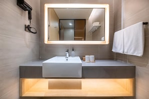 A modern bathroom with a large mirror, a sink, and a towel rack. - Ji Hotel (Shanghai)