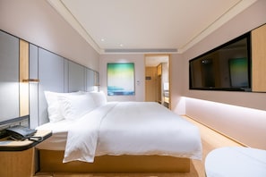 A modern hotel room with a large bed, a desk with a telephone, and a flat-screen TV mounted on the wall. - Ji Hotel (Shanghai)