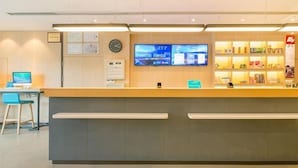 A reception desk with a computer, a clock, and a TV screen displaying information. - Hanting Hotel Shanghai The Bund Jiangxi Middle Roa (Shanghai)