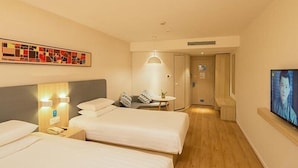 A hotel room with two beds, a desk, a chair, a TV, and a painting on the wall. - Hanting Hotel Shanghai The Bund Jiangxi Middle Roa (Shanghai)