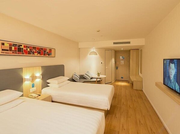A hotel room with two beds, a desk, a chair, a TV, and a painting on the wall.