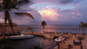 A beachfront resort with a dock, boats, and outdoor seating by the water. - Luxurious Caribbean 2 Bedroom 2 Bath Home (Islamorada)