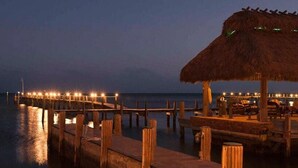 A pier extending into calm waters at dusk with a thatched-roof structure and seating area. - Luxurious Caribbean 2 Bedroom 2 Bath Home (Islamorada)