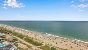 A beach with a clear sky, a pool area, and beach umbrellas. - Penthouse with an Amazing views! (Ocean City)