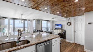 A modern kitchen with granite countertops, stainless steel appliances, and a view of the ocean. - Penthouse with an Amazing views! (Ocean City)