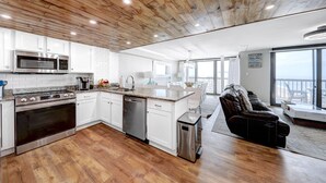A modern kitchen with white cabinets, stainless steel appliances, and a wooden ceiling. - Penthouse with an Amazing views! (Ocean City)
