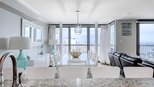 A modern dining area with a large table, white chairs, and a view of the ocean. - Penthouse with an Amazing views! (Ocean City)