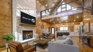 Amplia sala de estar con chimenea, una mesa de comedor y una cocina al fondo.