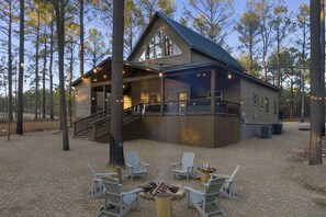Une cabane dotée d’une terrasse couverte, de sièges extérieurs et d’un escalier menant à l’entrée.