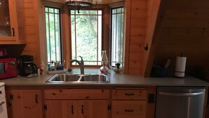 Una cocina con armarios de madera, un lavamanos de acero inoxidable y un lavavajillas empotrado.