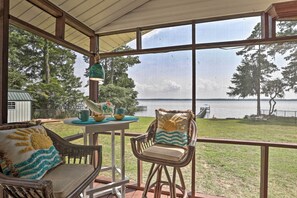 A covered patio with wicker furniture, a table with a teapot and cups, and a view of a lake. - Idyllic Waterfront Escape w/ Private Boat Dock! (Summerton)