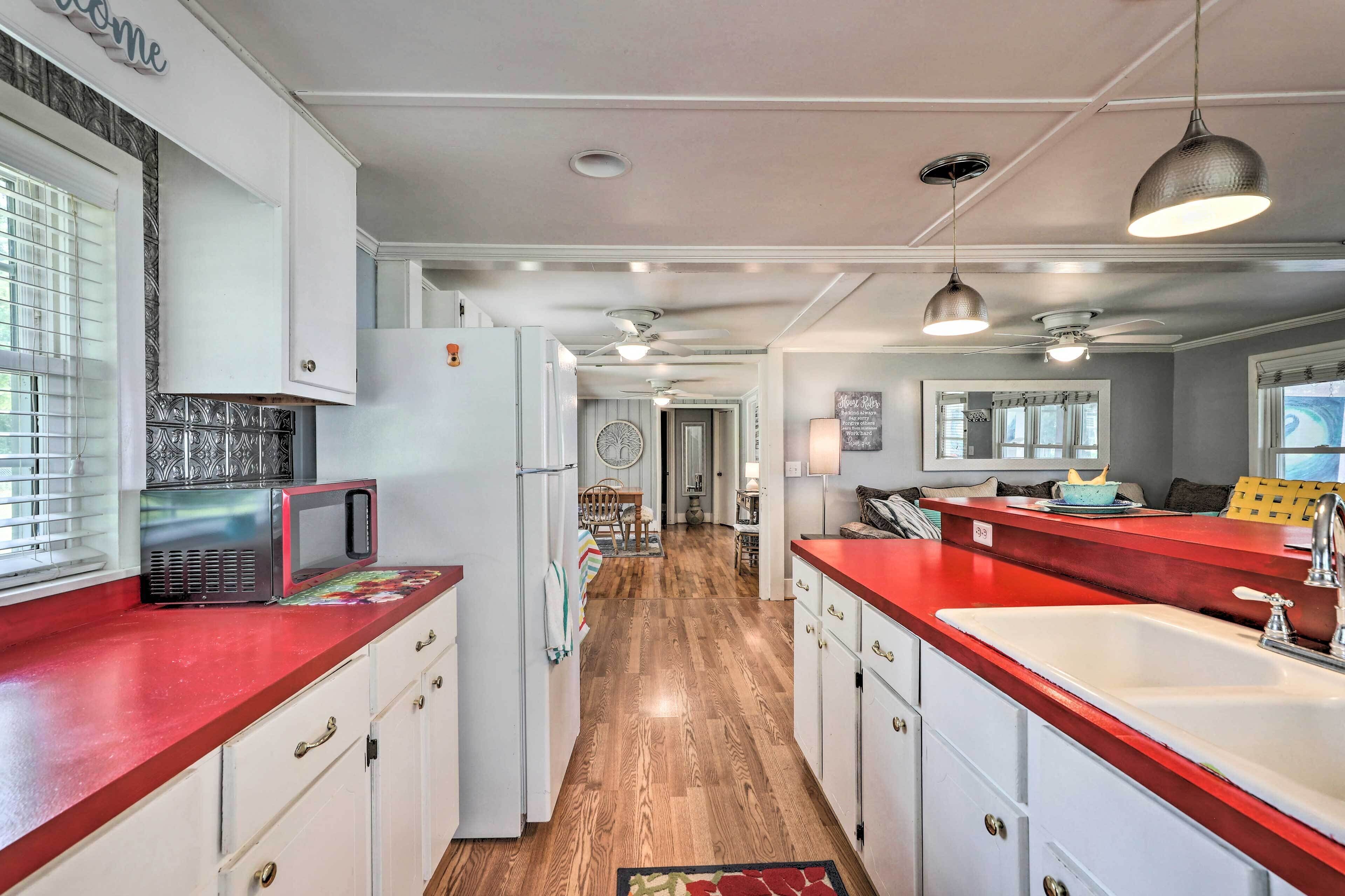 A kitchen with white cabinets, a red countertop, and a wooden floor.