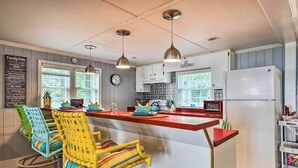 Een keuken met een rood kookeiland, witte kasten en een bord met gezinsregels aan de muur.