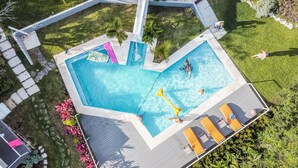 Une piscine rectangulaire dotée d’une terrasse en bois et de chaises longues.