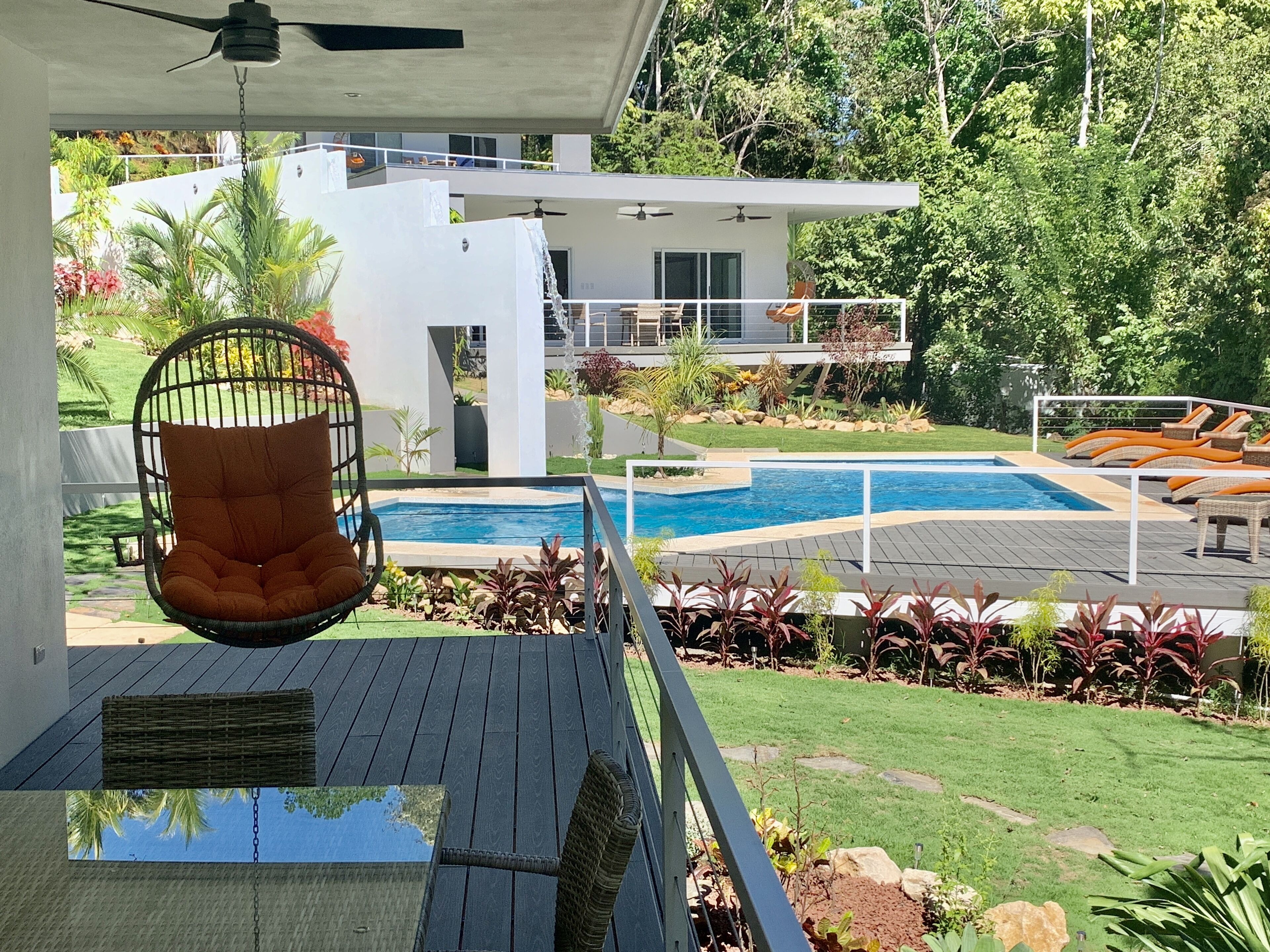Une maison moderne avec une piscine, un fauteuil suspendu et une terrasse.