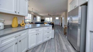 A modern kitchen with white cabinets, a stainless steel refrigerator, and a central island. - Kickin' It on Kindra! Modern 3 Bedroom New Build! (Cottonwood)