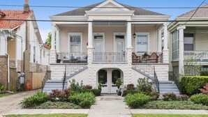 Une maison à deux étages avec une entrée centrale, un porche couvert et un petit jardin à l’avant.