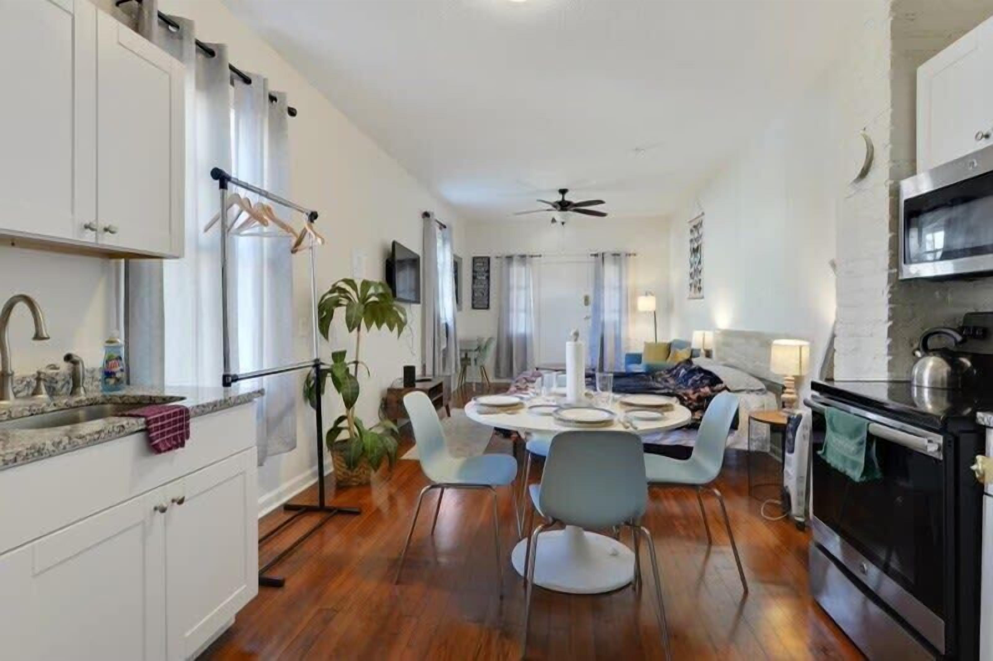 A modern kitchen with white cabinets, a dining area with a round table, and a black oven.