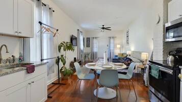 A modern kitchen with white cabinets, a dining area with a round table, and a black oven.