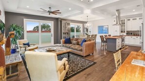 A spacious living area with a large sofa, a dining table, and a kitchen in the background.