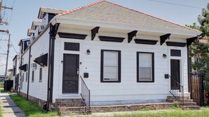 A two-story white house with black trim, a red-tiled roof, and a front porch with steps.