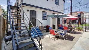 A residential building with a patio area featuring outdoor furniture and a staircase. - Charming Central 2BR | Courtyard | Pet Friendly (New Orleans)