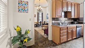 A kitchen with wooden cabinets, a stainless steel dishwasher, and a marble countertop. - Lovely 3BD | Steps to St. Charles | Gated Parking (New Orleans)
