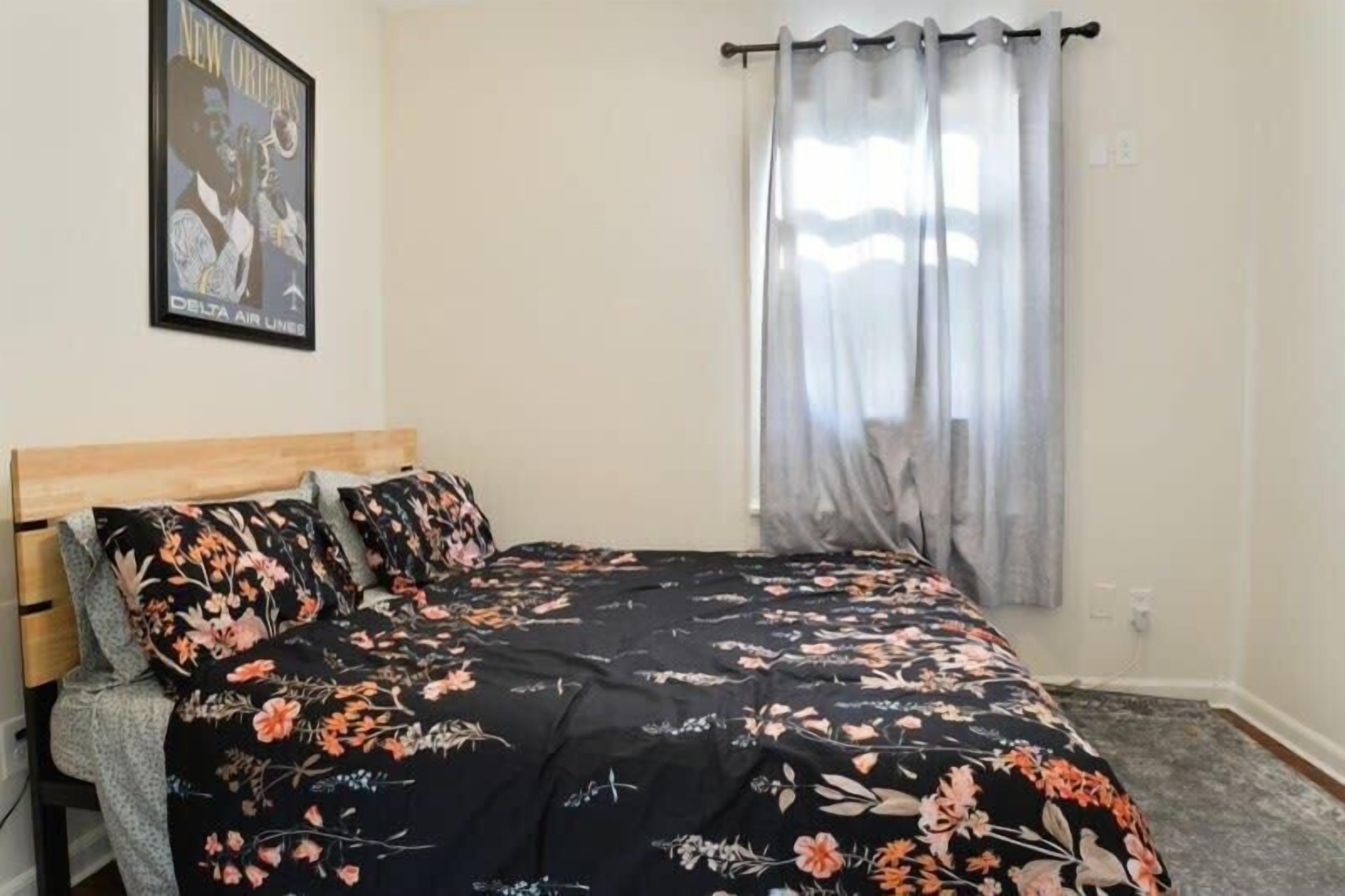 Un dormitorio con cabecera de madera, colcha estampada con motivos florales y un cartel de Delta Air Lines en la pared.