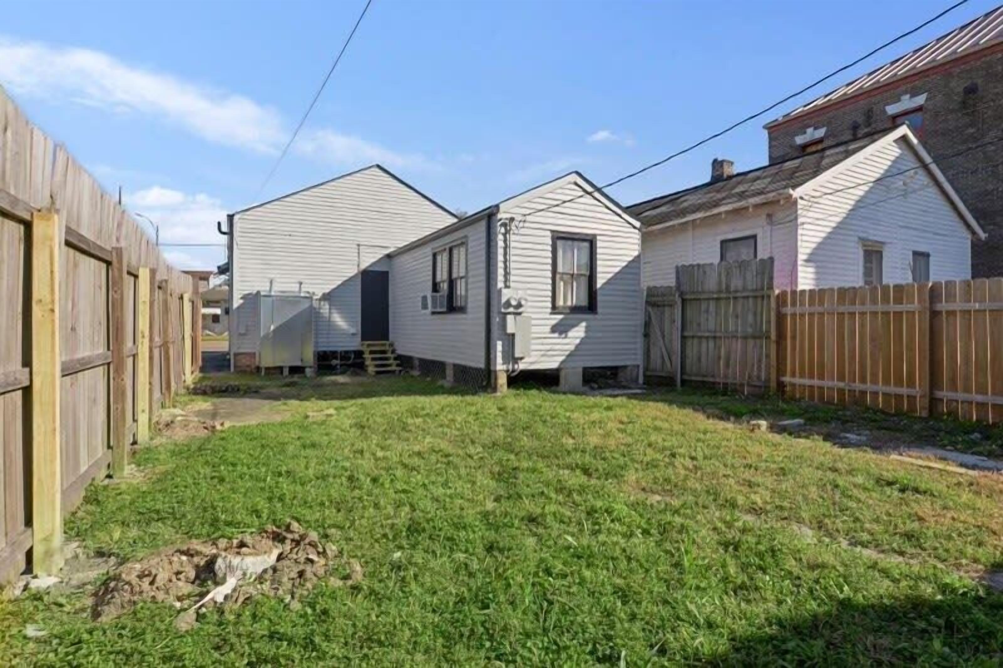 A residential area with two single-story houses, a wooden fence, and a grassy yard.