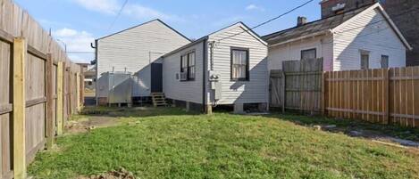 A residential area with two single-story houses, a wooden fence, and a grassy yard.