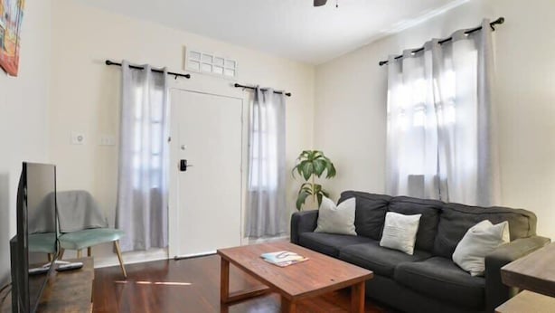 A living room with a sofa, coffee table, and a television. - 2BR Steps to Music + Food | Pet Friendly (New Orleans)