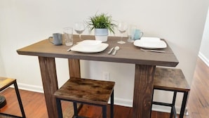 A dining table with four chairs, a potted plant, and a small stool. - 2BR Steps to Music + Food | Pet Friendly (New Orleans)